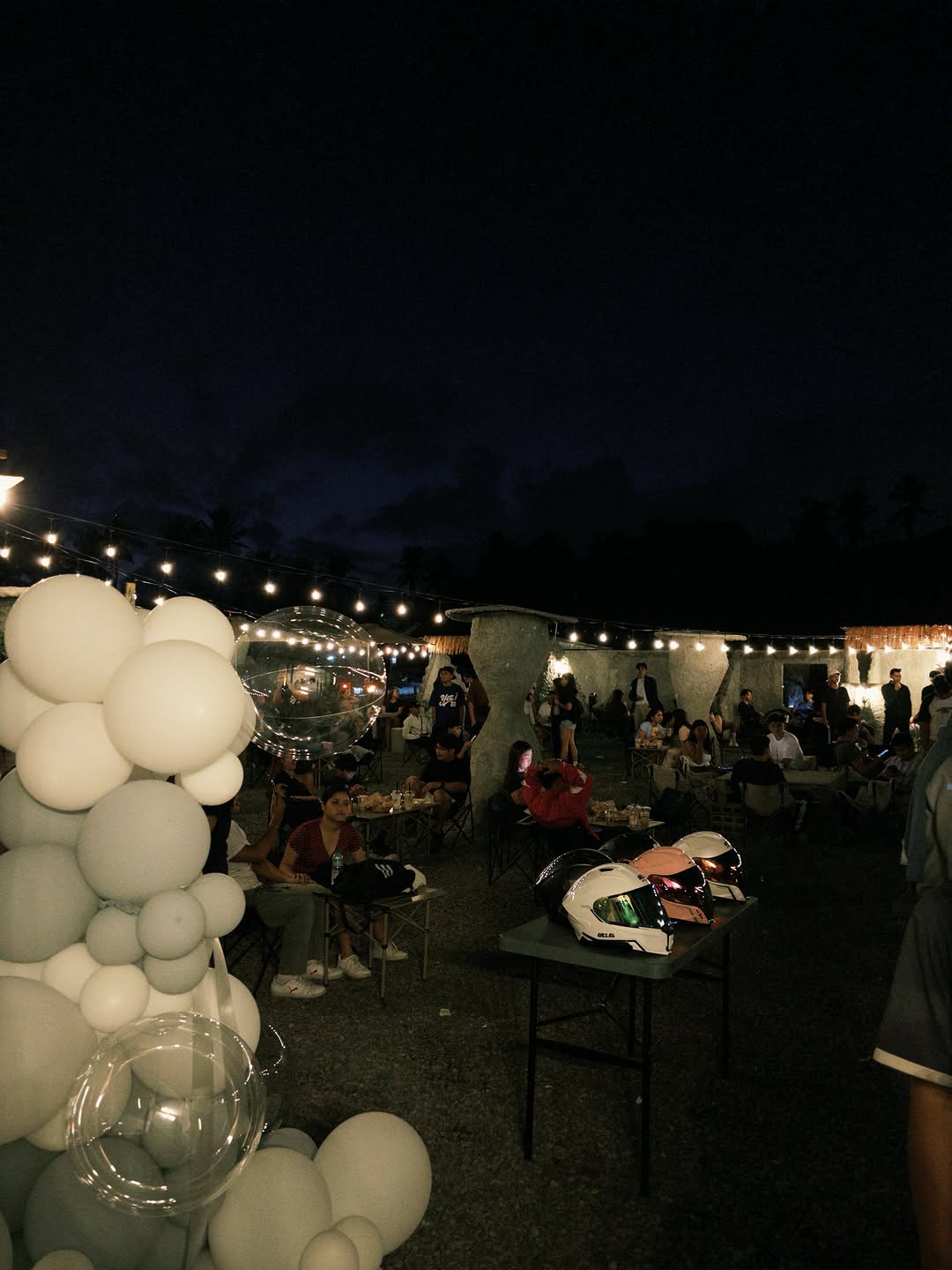 Opening night at Moon Coffee 2.0 — outdoor tables filled with guests under string lights and white balloon clusters